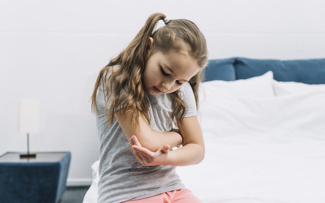 **enfant avec eczéma sur les bras se grattant la peau**